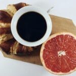 Kawa z rogalikiem i połówką grejpfruta na drewnianej desce