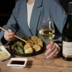 Kobieta jedząca sushi i pijąca białe wino przy eleganckim stole