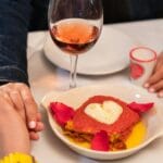 Para przy romantycznej kolacji z różowym winem i sercem na talerzu