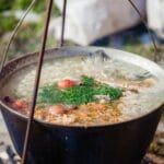 Kociołek domowego bulionu ziołowego gotujący się na ognisku