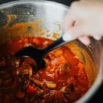 Mieszanie warzywnego gulaszu z pomidorami i przyprawami w garnku