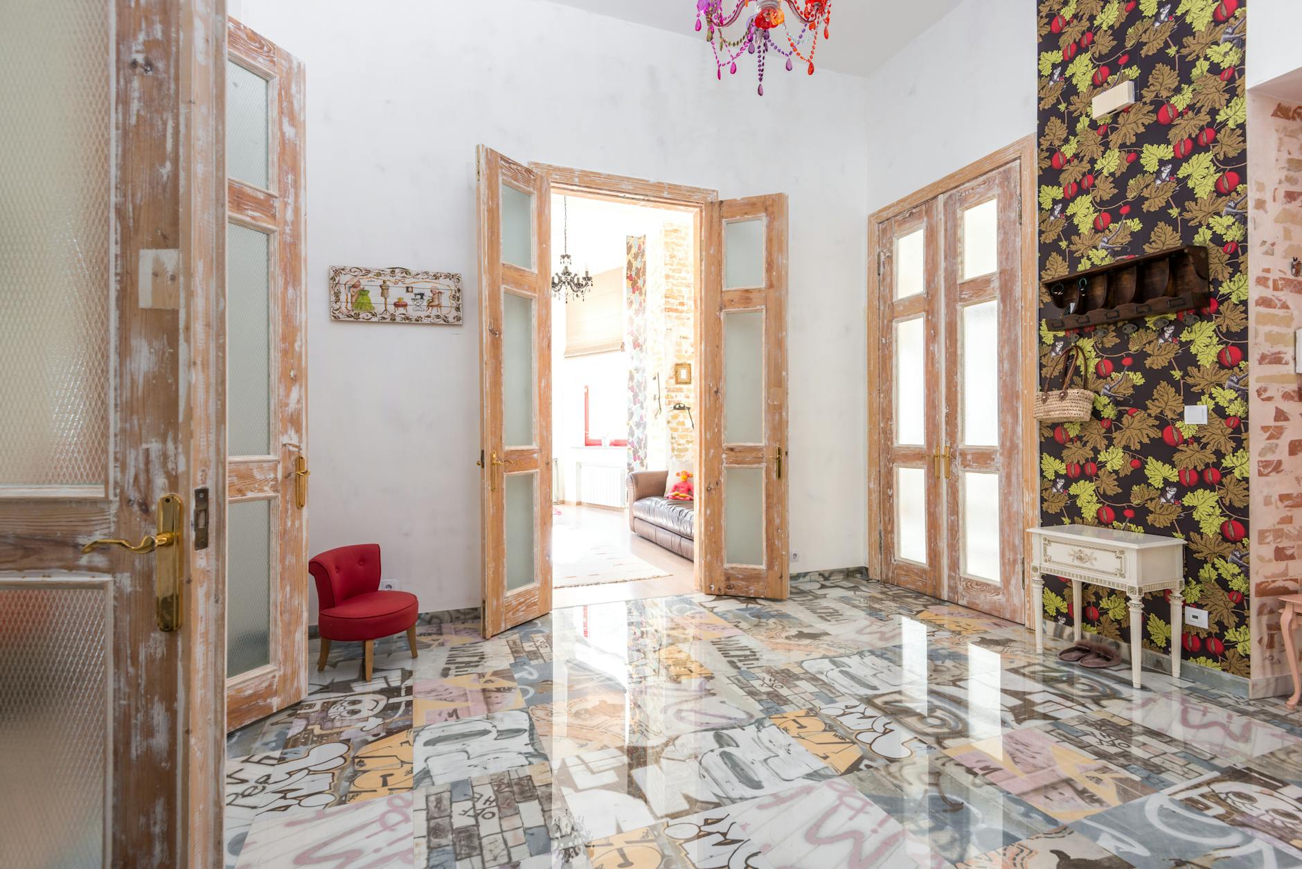 Kolorowy, eklektyczny salon z wzorzystą tapetą i drewnianymi drzwiami