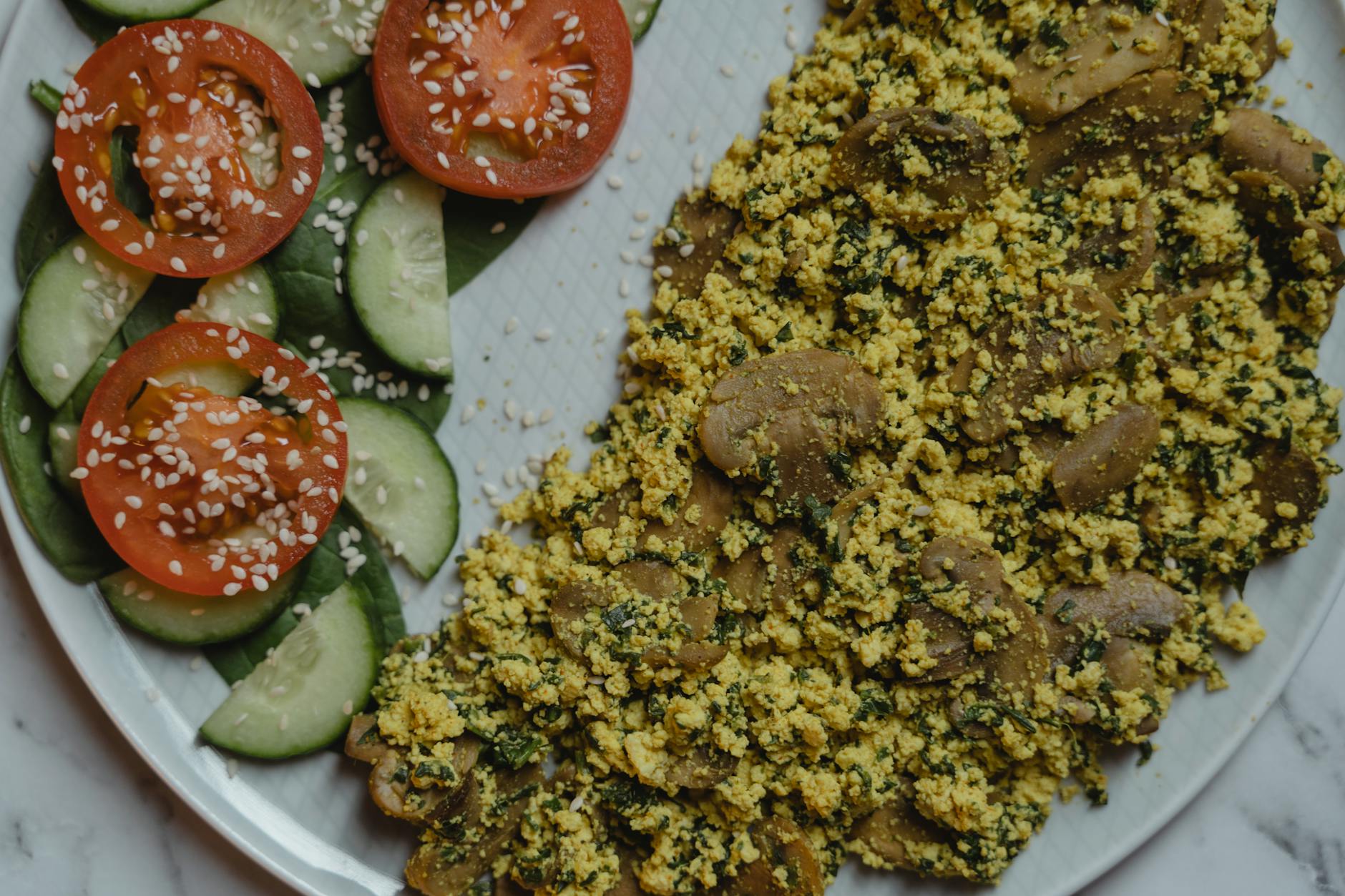 Wegański talerz z tofucznicą, ogórkiem i pomidorami na marmurowym blacie