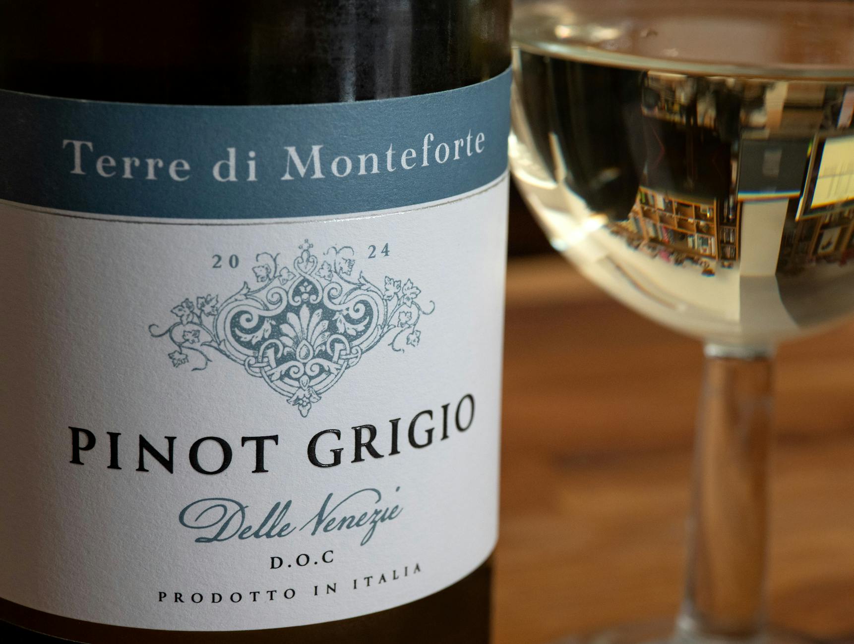 Zbliżenie butelki włoskiego Pinot Grigio i kieliszka na rozmytym tle